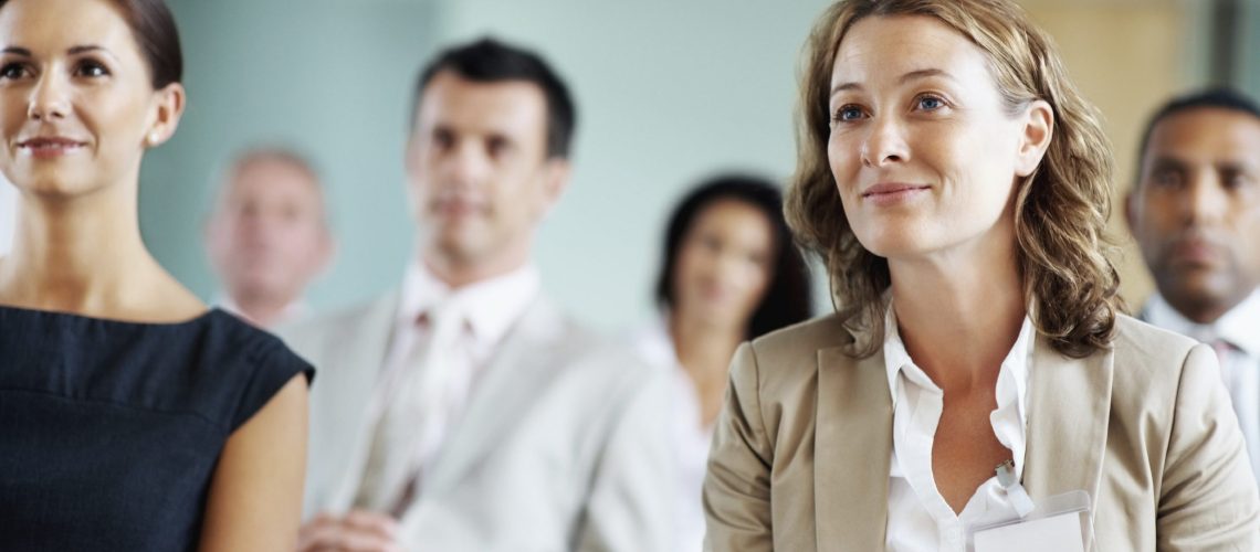 Portrait of a two middle aged business women with their blur team at a seminar